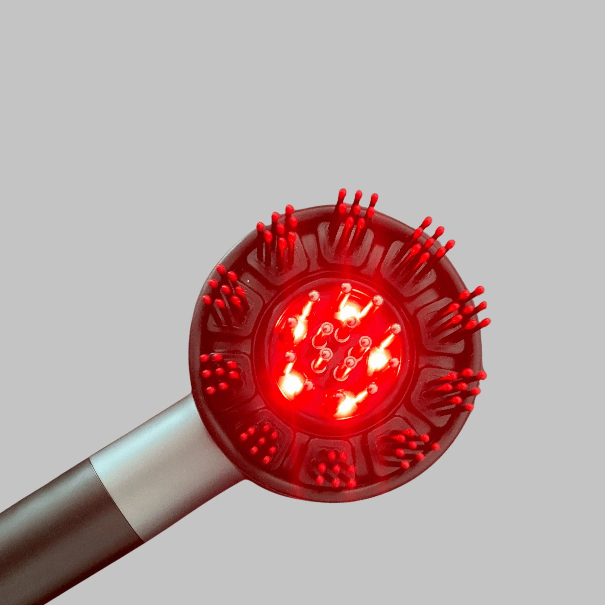 Red light scalp massager tool with multiple nozzles on a gray background